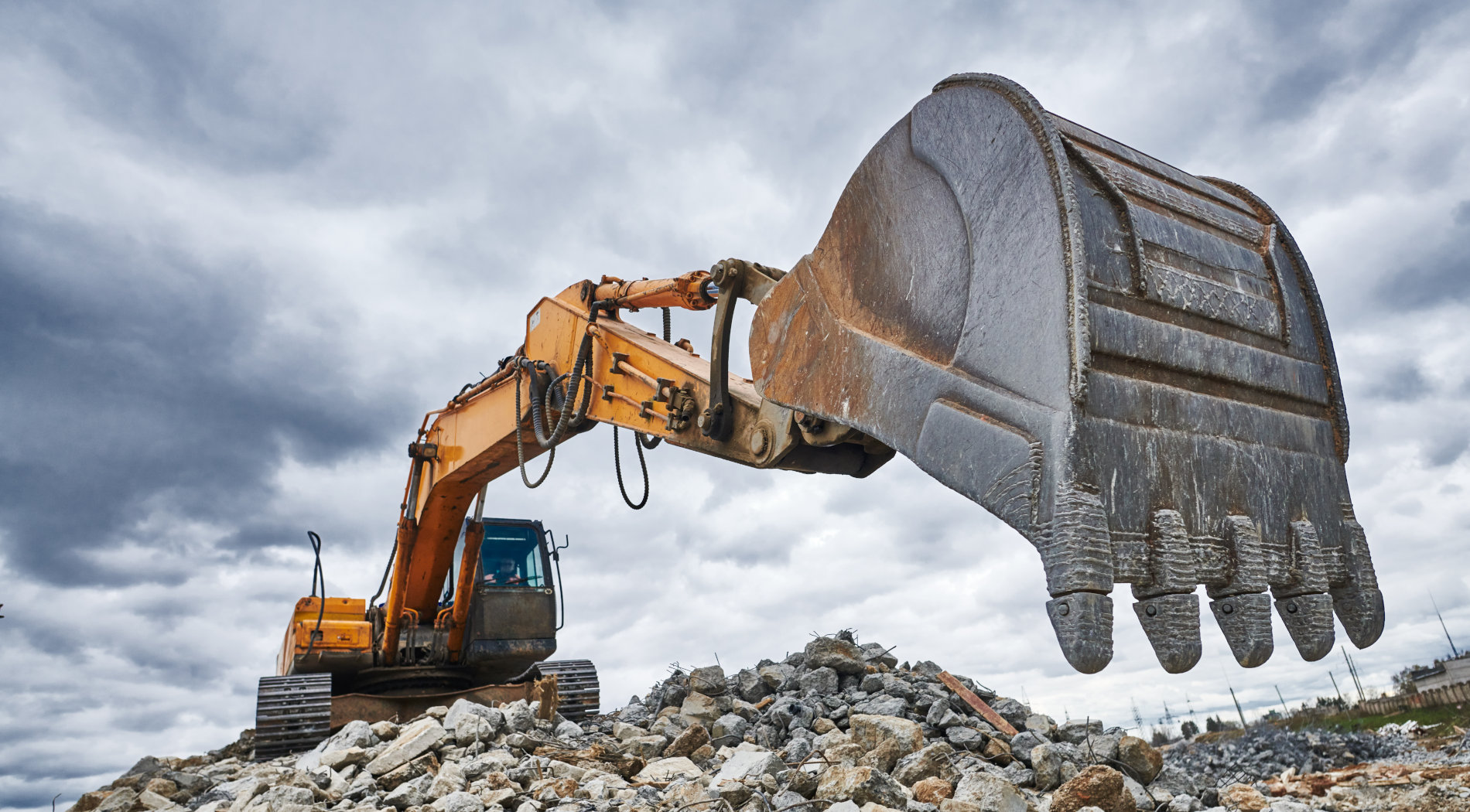 A leasable excavator arm reaches towards the camera, ready to be financed at Thomcat.