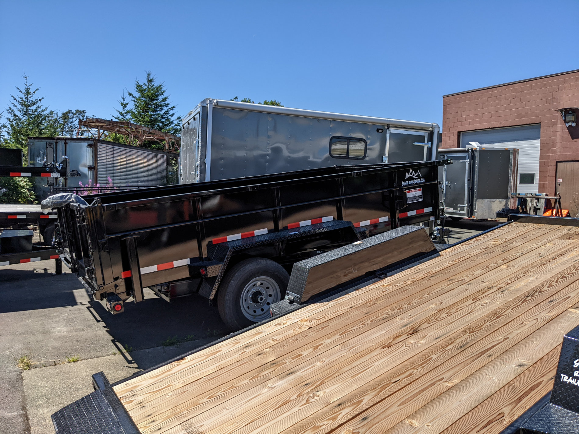 tilt-deck-trailer-assorted-utility-trailers-at-thomcat A tilt deck trailer along with other assorted trailer types at the Thomcat lot in Langford, BC